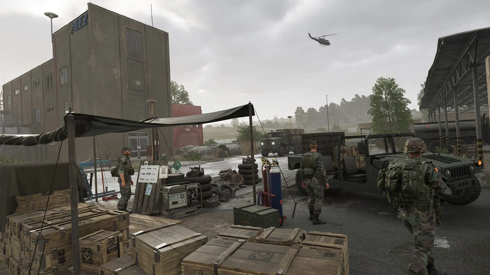 Arma Reforger Server Setup: soldiers walk through a supply depot of ammunition crates under a tarp, with a Humvee, a cargo truck and a helicopter overhead beside a concrete building